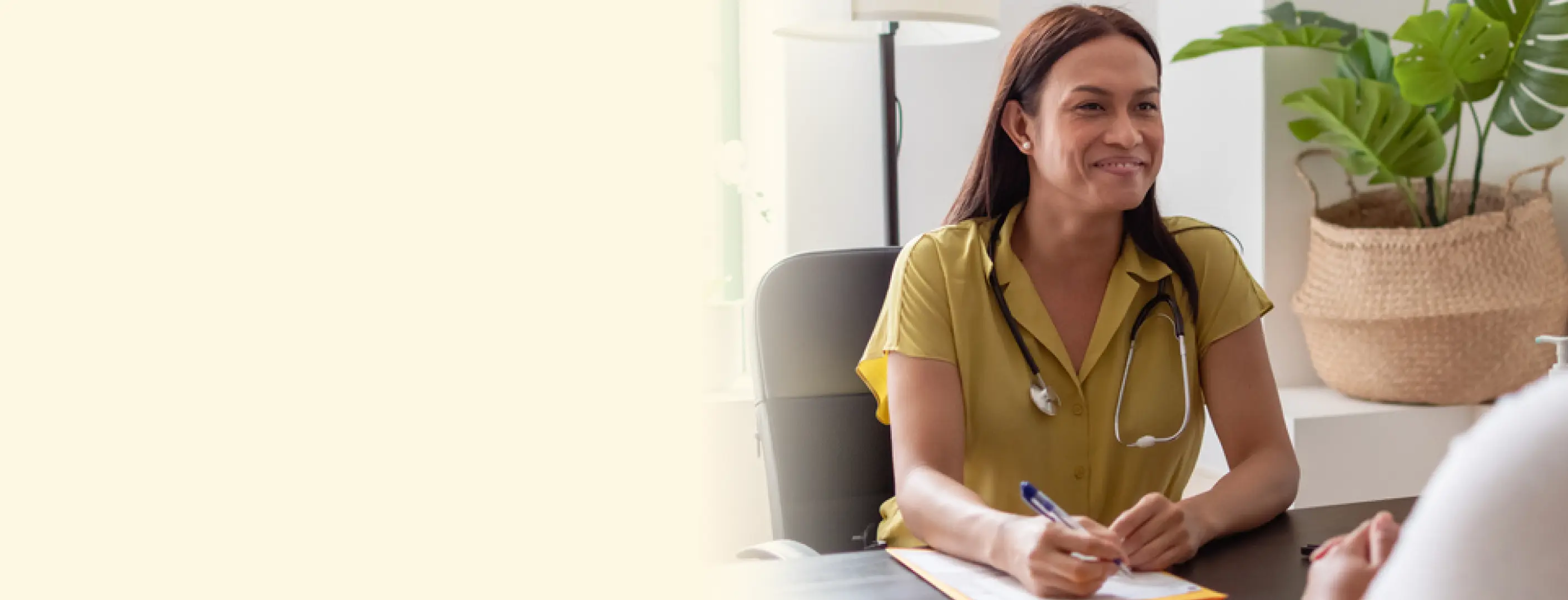 Smiling healthcare professional with a stethoscope, taking notes during a consultation